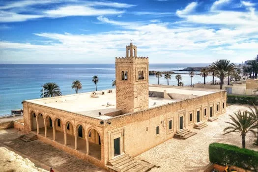 Serene view of a historic mosque in Monastir, Tunisia, with azure coastline.